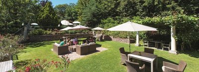 Garten mit Sonnenschirmen und Gästen vom Hotel Lambrechtshof in Eppan in Südtirol Urlaub in alpetour-eigenen Hotels