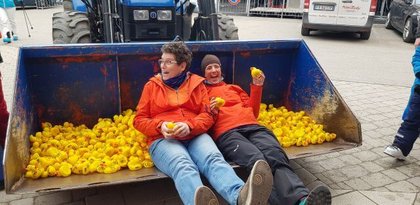 Zwei Alpetour-Mitarbeiterinnen in Radladerschaufel mit vielen Badeenten